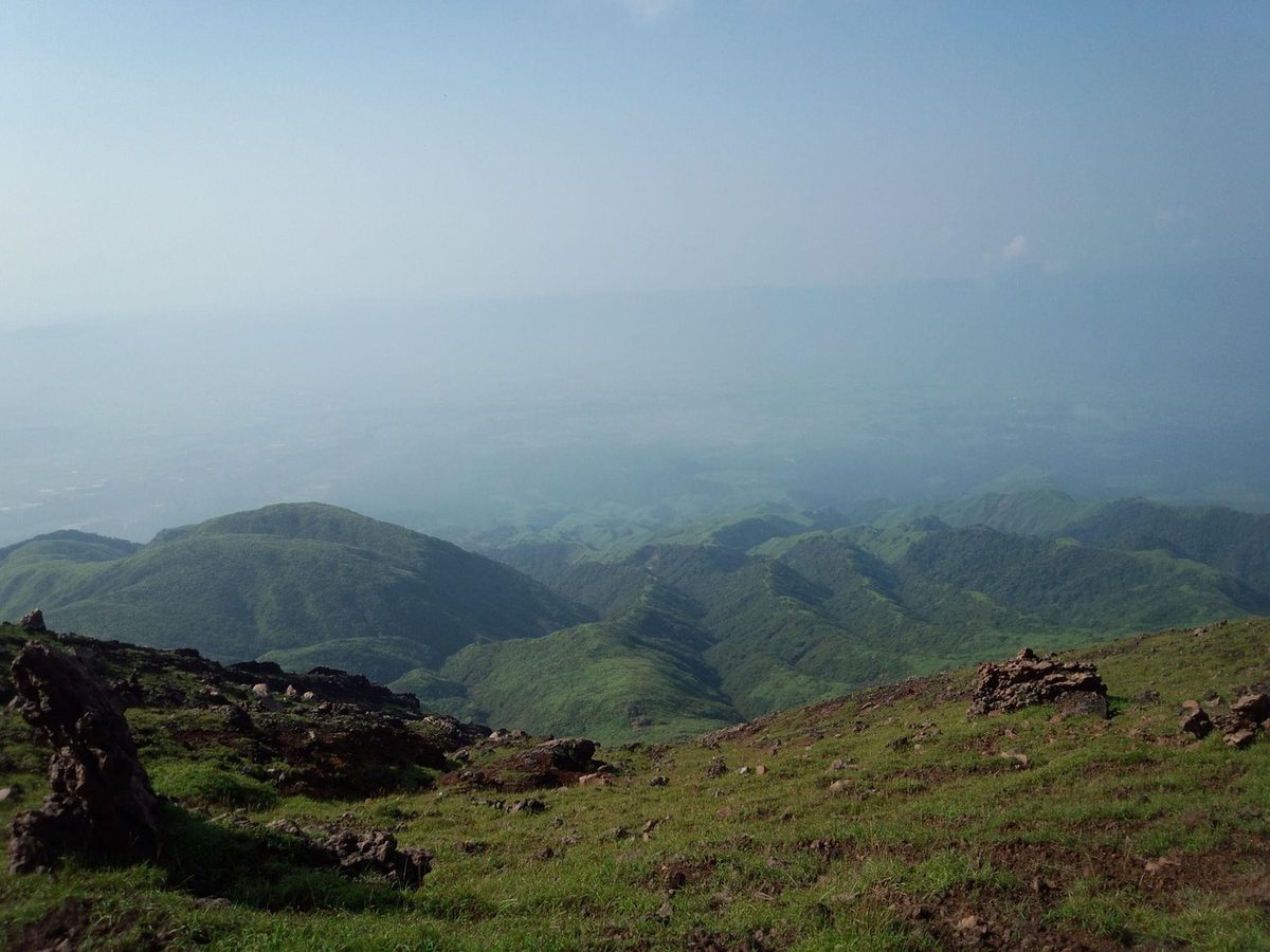 Green meadow stretching across the Aso caldera with mountain ridge