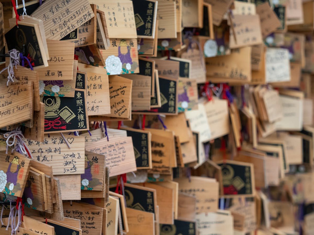 Wooden ema prayer plaques hanging at a Japanese shrine, covered in handwritten wishes
