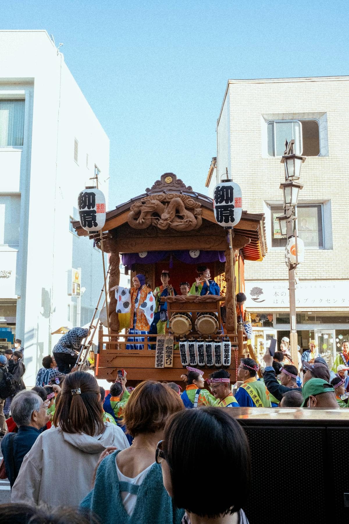 Japanese festival float being paraded through a street with drummers