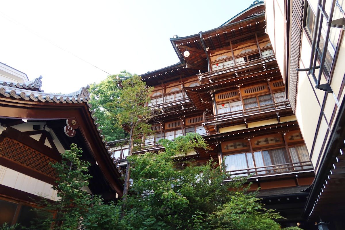 Wooden exterior of a traditional Japanese ryokan surrounded by greenery