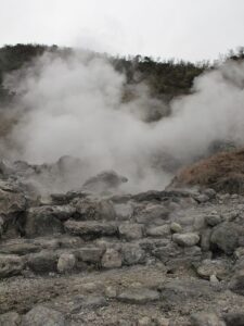Unzen Jigoku steam vents with barren rocky terrain and surrounding hills